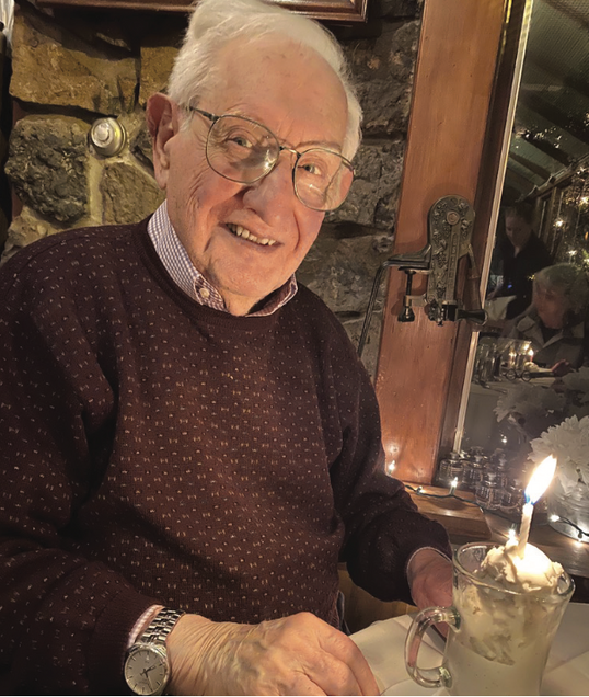 elderly man wearing a sweater with a cup of ice cream with a lit candle