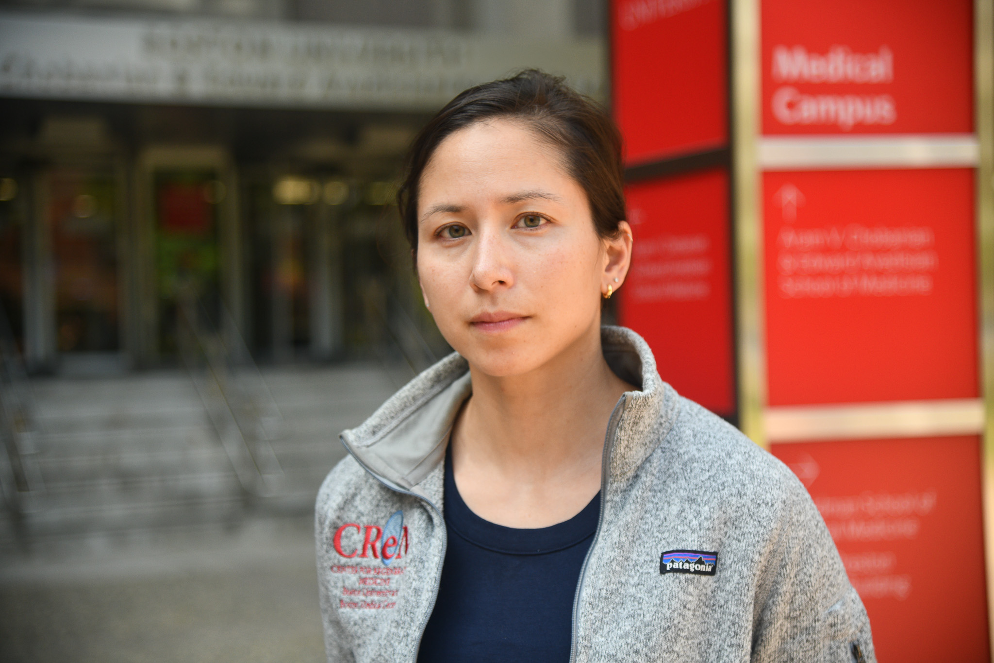 Portrait of Lauren Ayers wearing gray fleece jacket with CReM embroidery outside of Instructional building