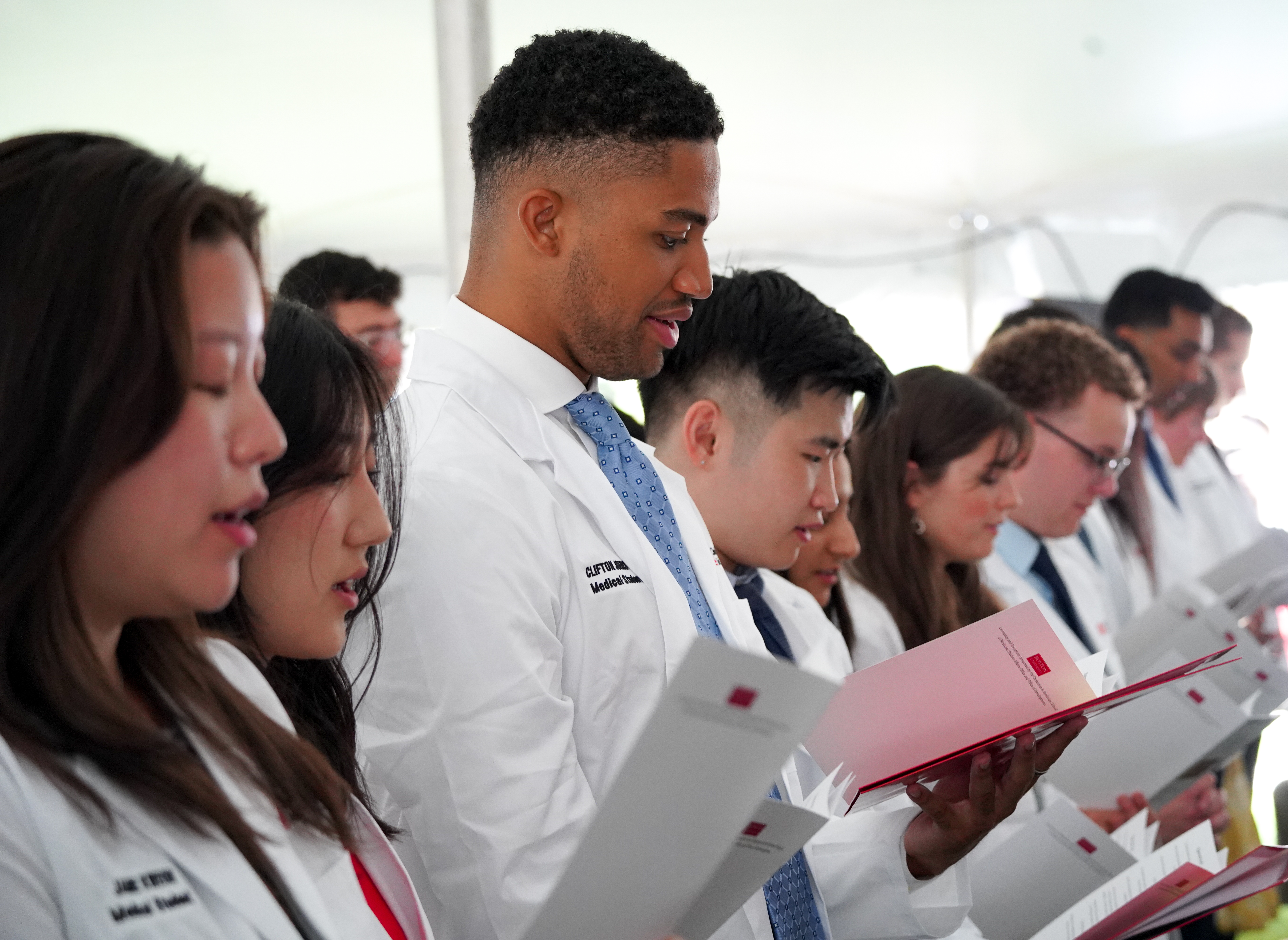 Students in whitecoats read hippocratic oath