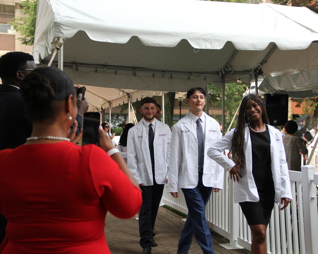Three students wearing whitecoats pose for pictures