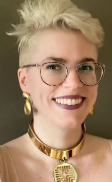 Woman with short blond hair, eyeglasses, gold earrings and necklace smiling broadly.
