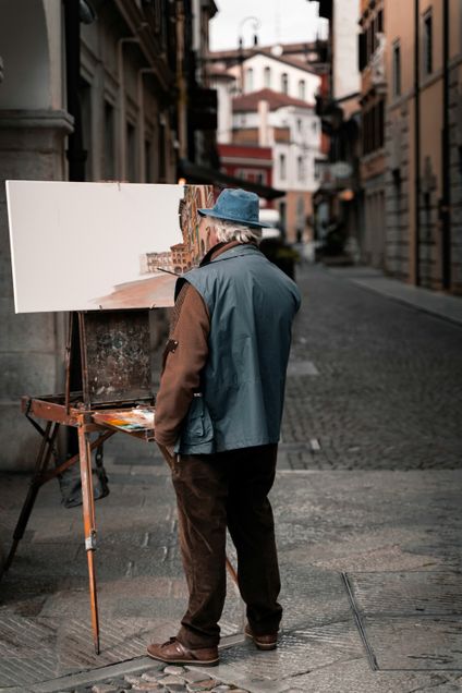 Older man painting canvas outside