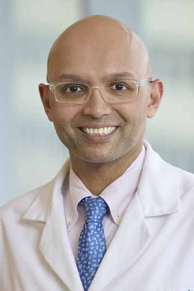 Omar Siddiqi wearing a whitecoat, smiling broadly