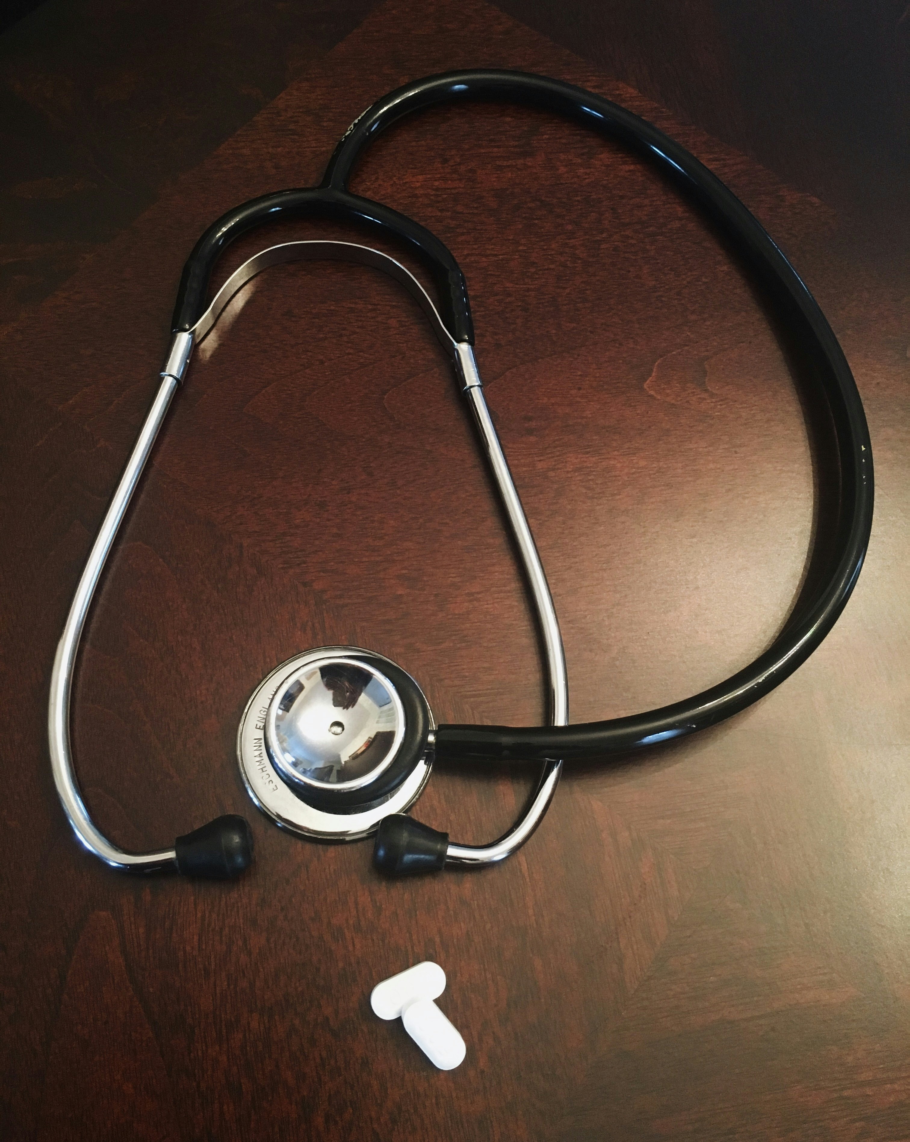 Stethoscope next to two white capsule pills