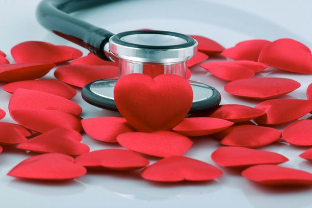 silver stethoscope surround by many small red fabric hearts