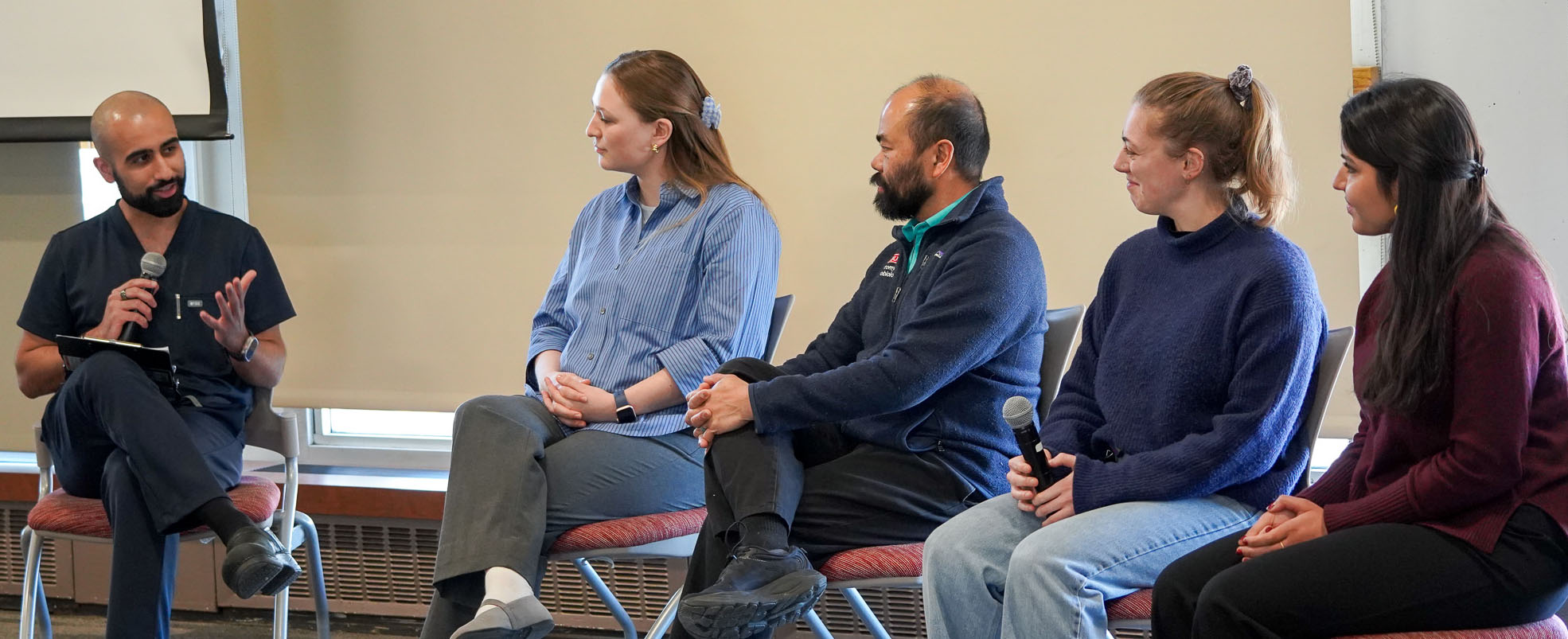 five people sitting in chairs holding microphones