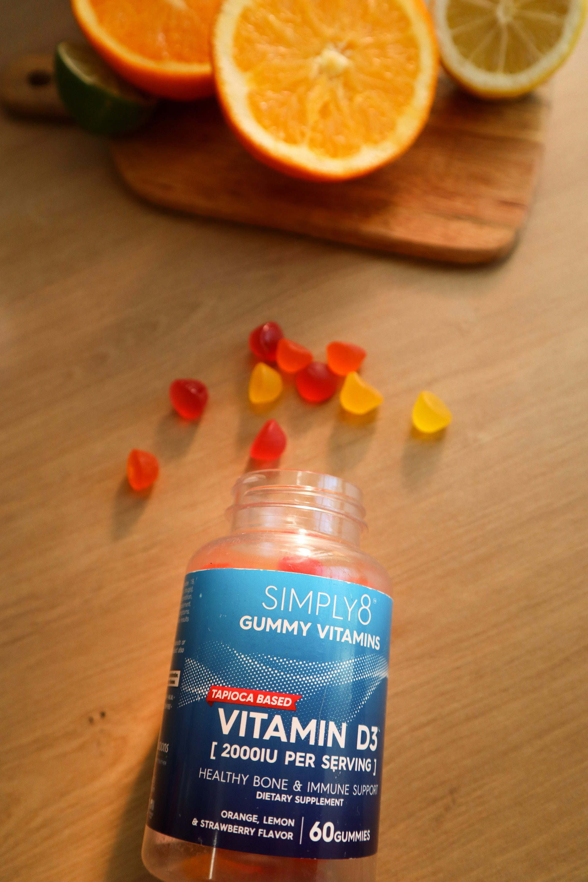 Bottle of Vitamin D gummies next to sliced oranges.