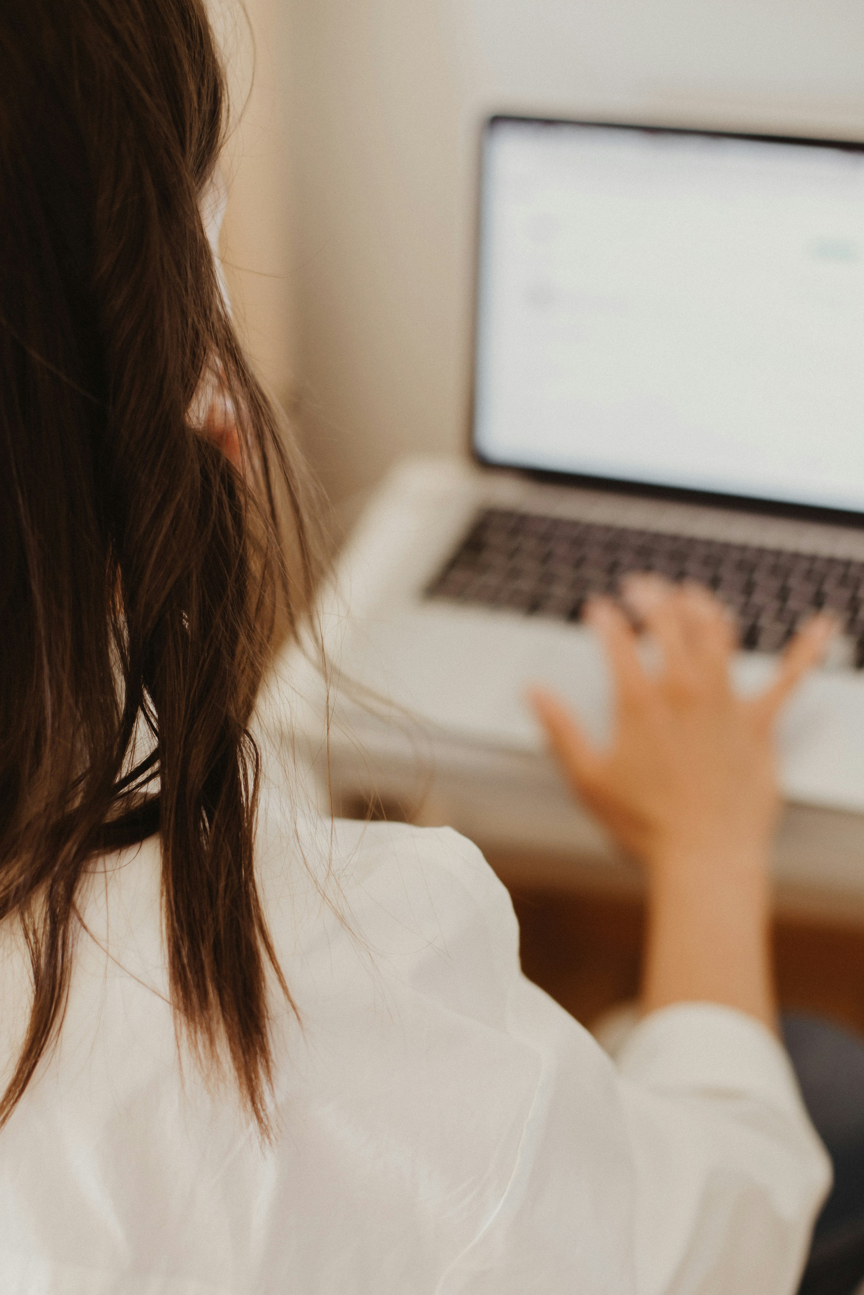 Back of woman's head and hands on laptop, slightly blurry