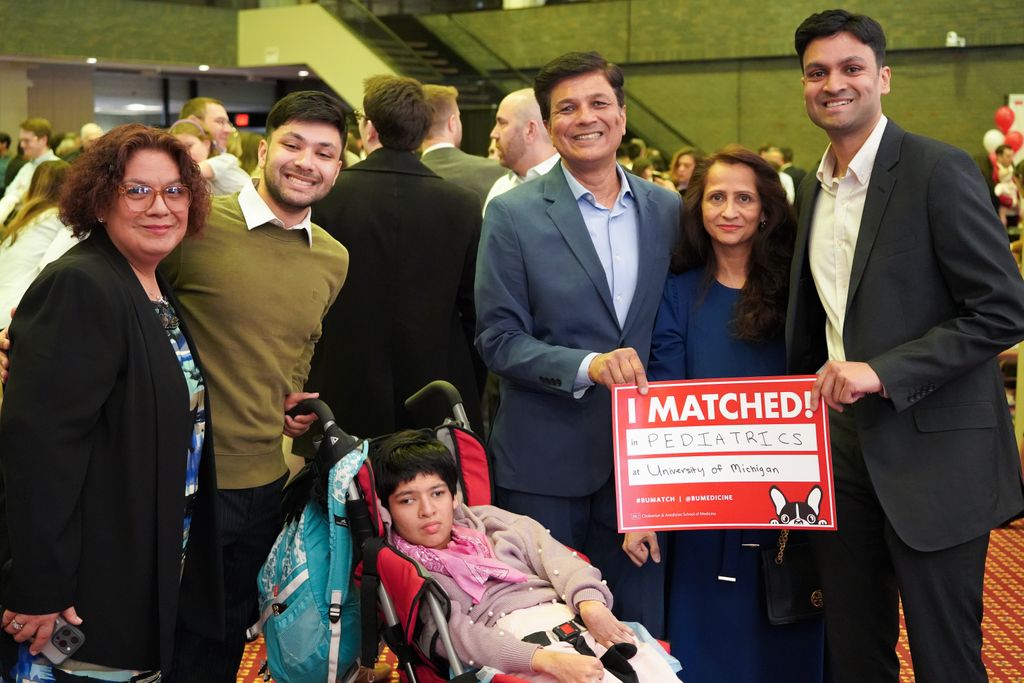 Student surrounded by family holding match poster