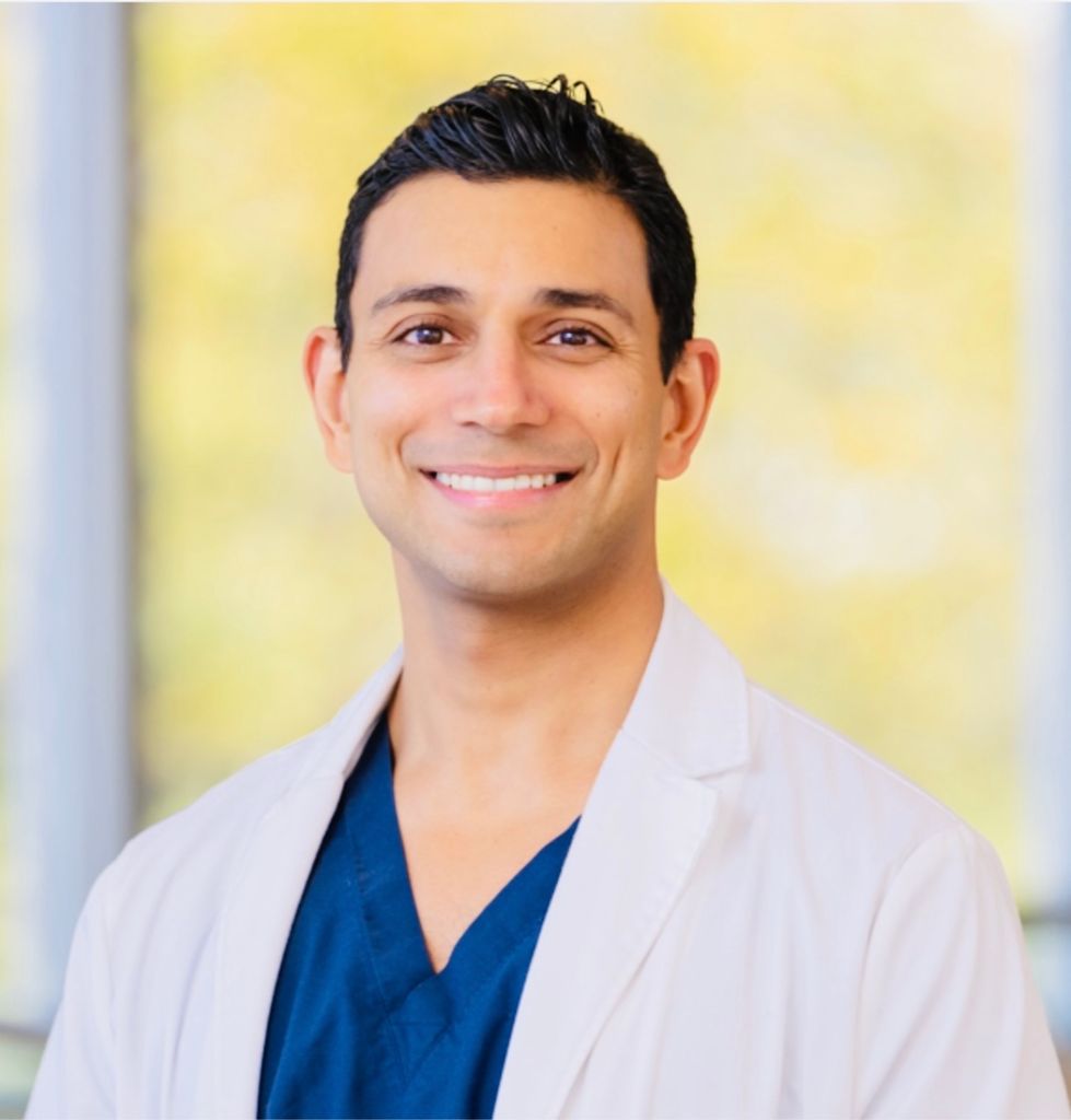 Dr. Sehgal in dark blue scrubs and whitecoat