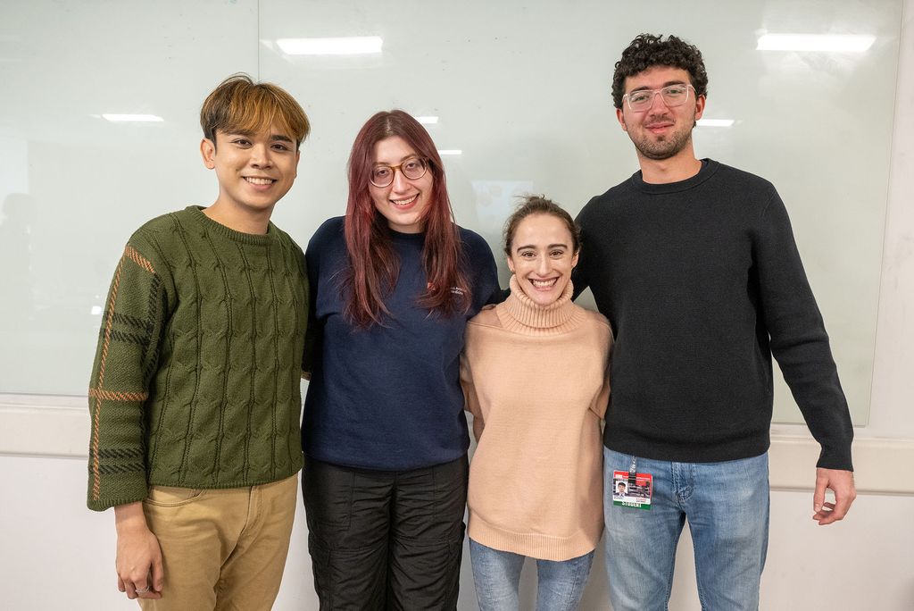 four students dressed casually standing together smiling