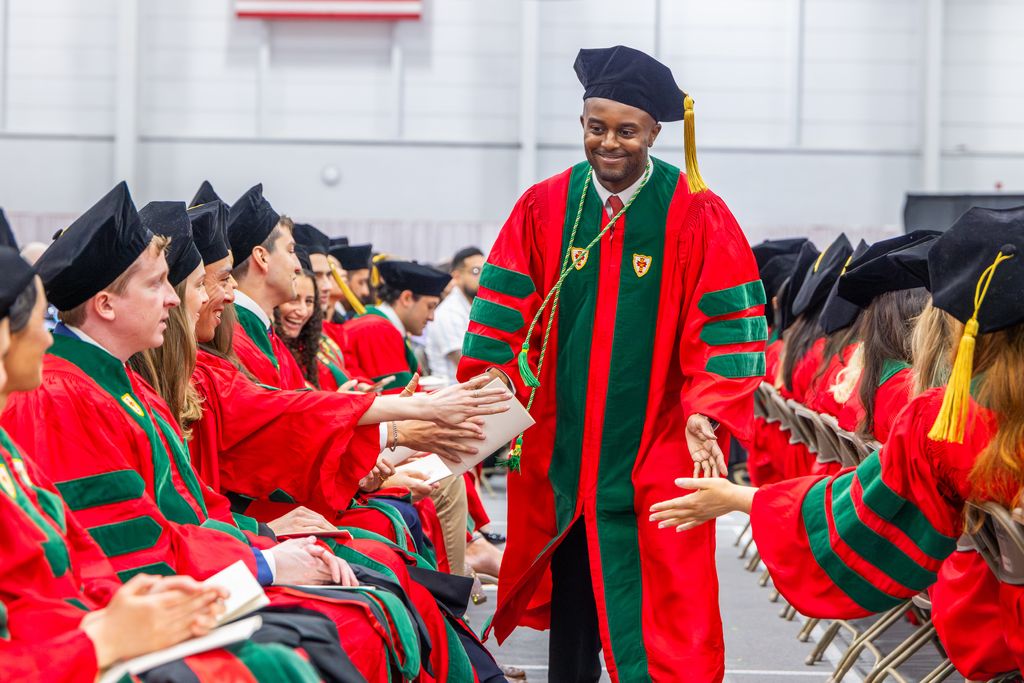 MD Student Commencement speaker walking down row high-fiving fellow students