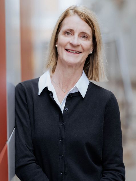 Portrait of Monica Pessina wearing dark jacket with white blouse, straight blond hair, similing