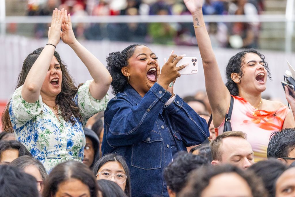 Three people standing cheering their friend/family