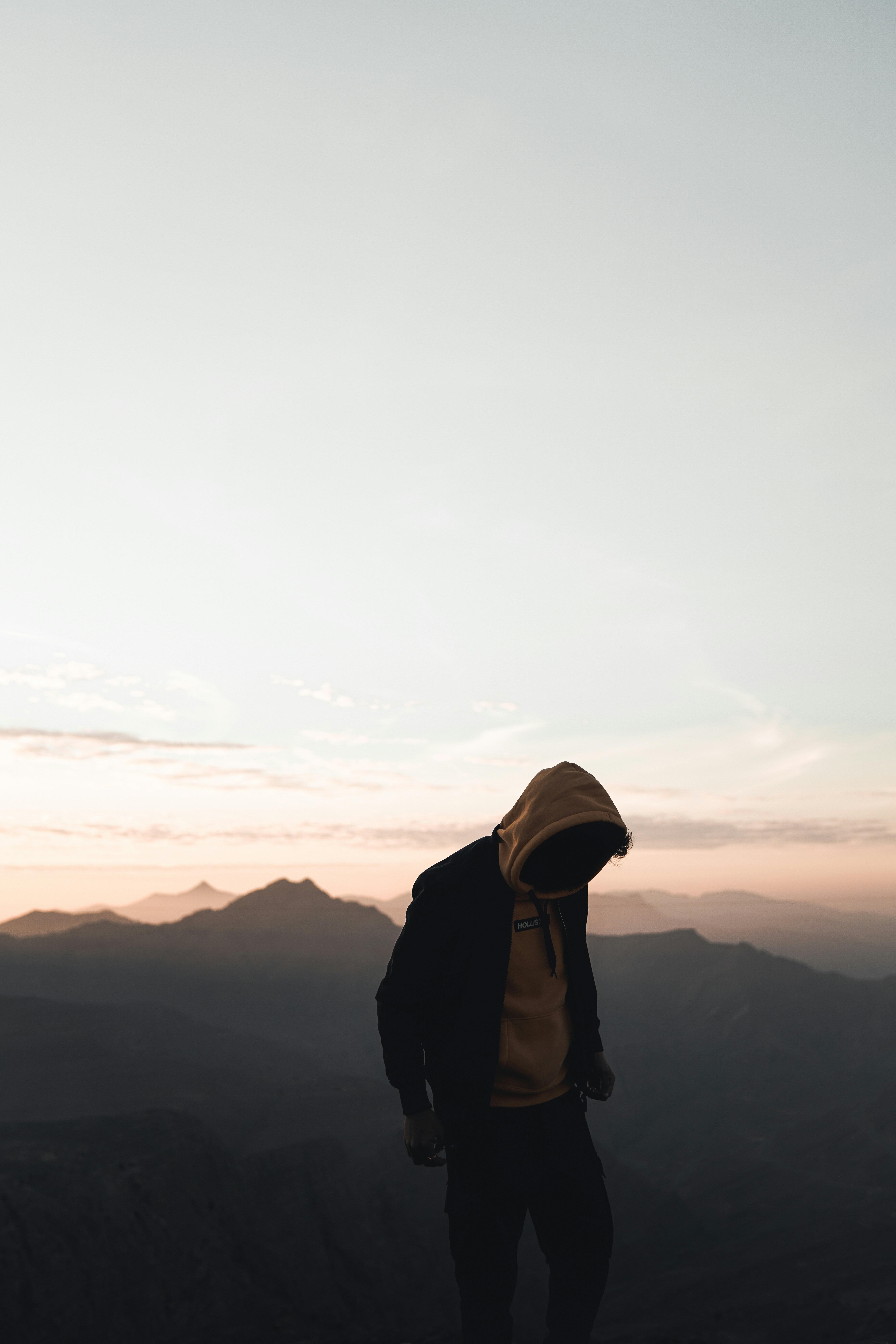 Person hunched over against sunsetting background
