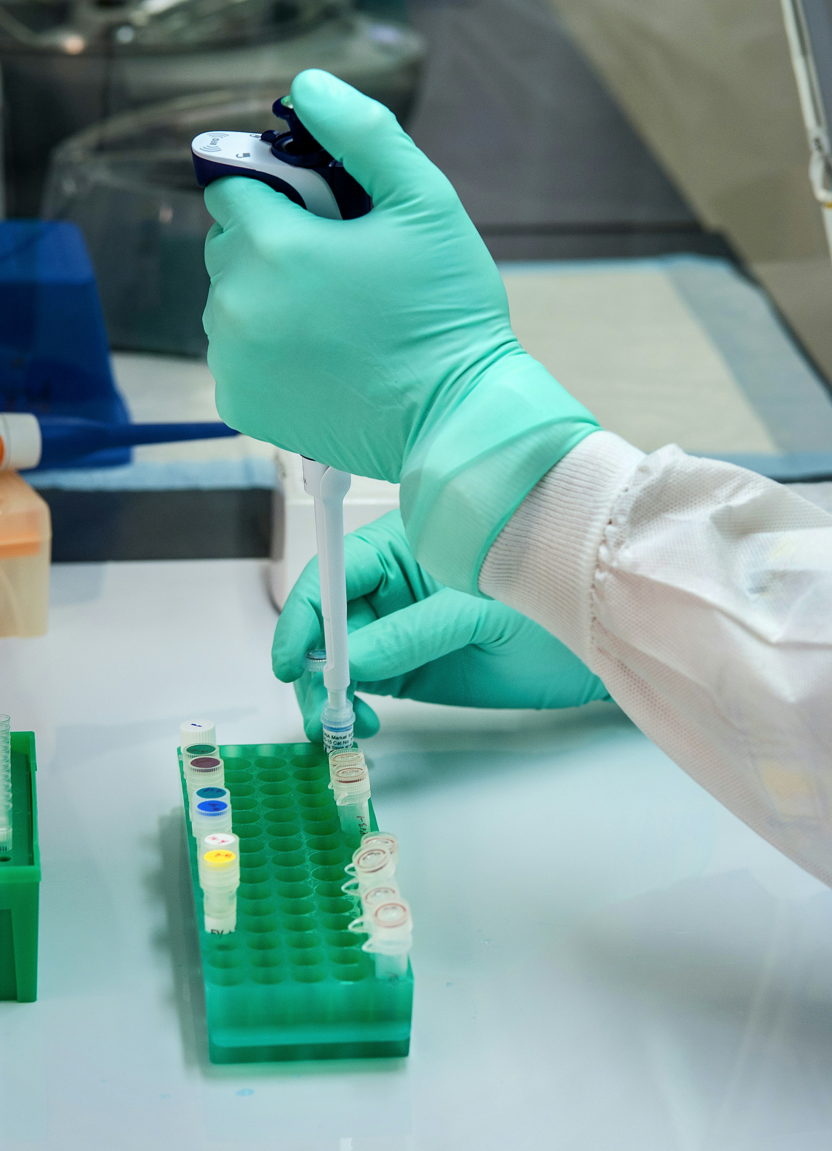 Green gloved hand holding test tube