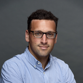 head and shoulders of man with blue shirt and eyeglasses