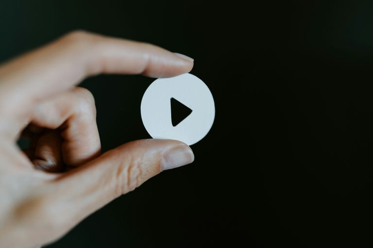 Hand holding video play button triangle