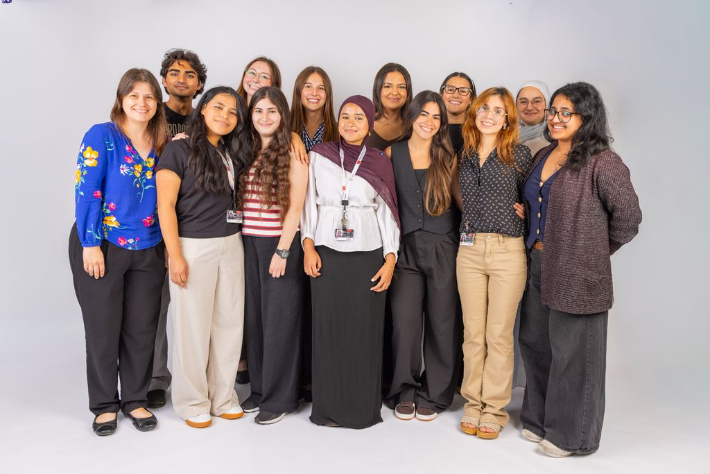 Group of 11 students and two faculty/staff standing together smiling