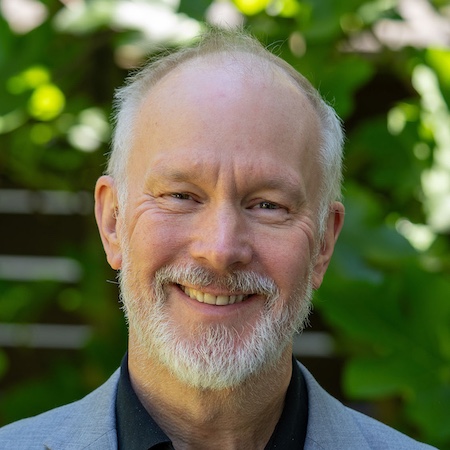 head and shoulders image of man with gray hair and facial hair smiling