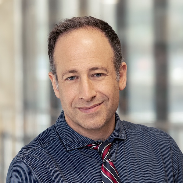 head and shoulders of man wearing dark shirt striped tie short dark hair