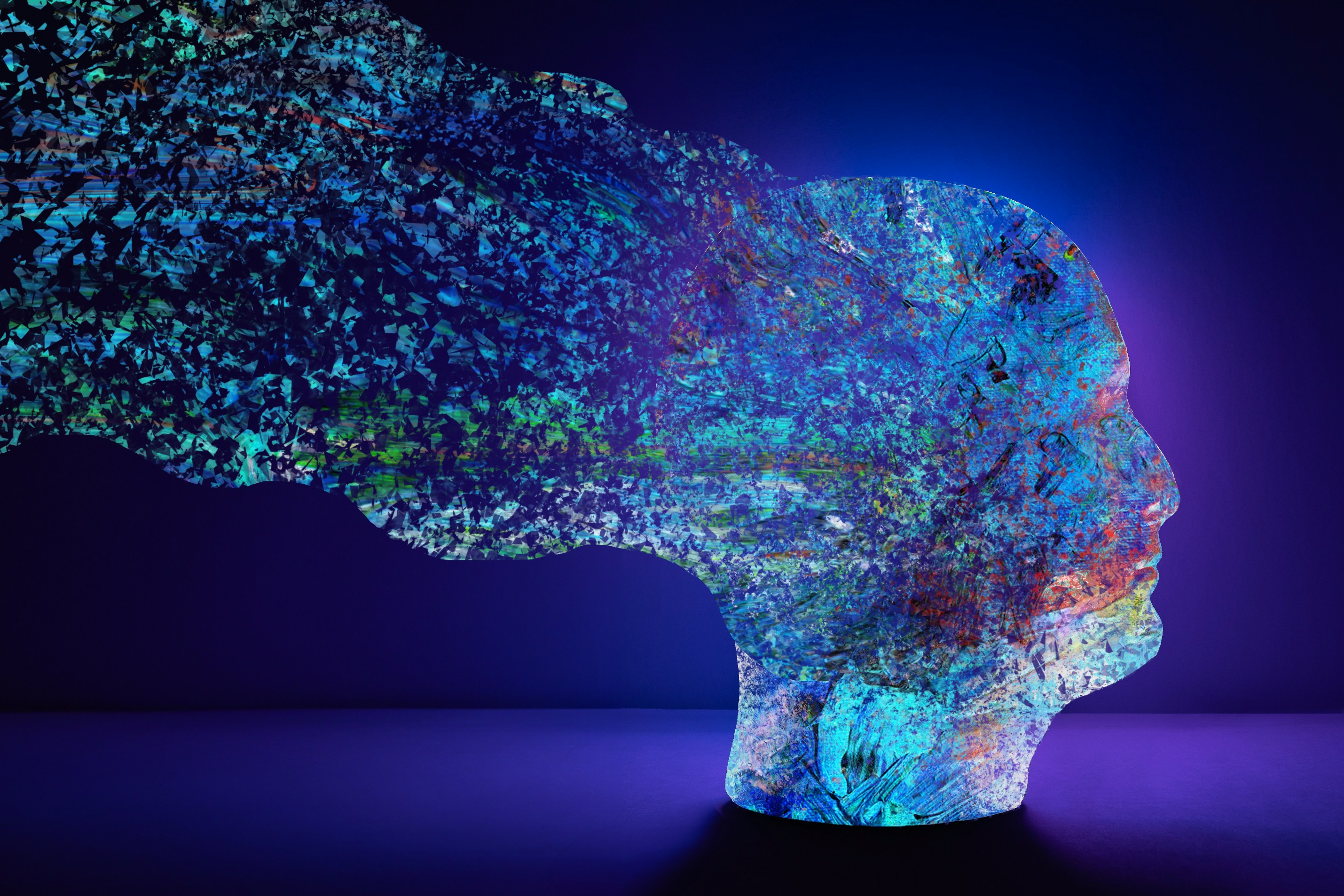 abstract head sculpture against blue background with blue, purple, green flecks of light emanating