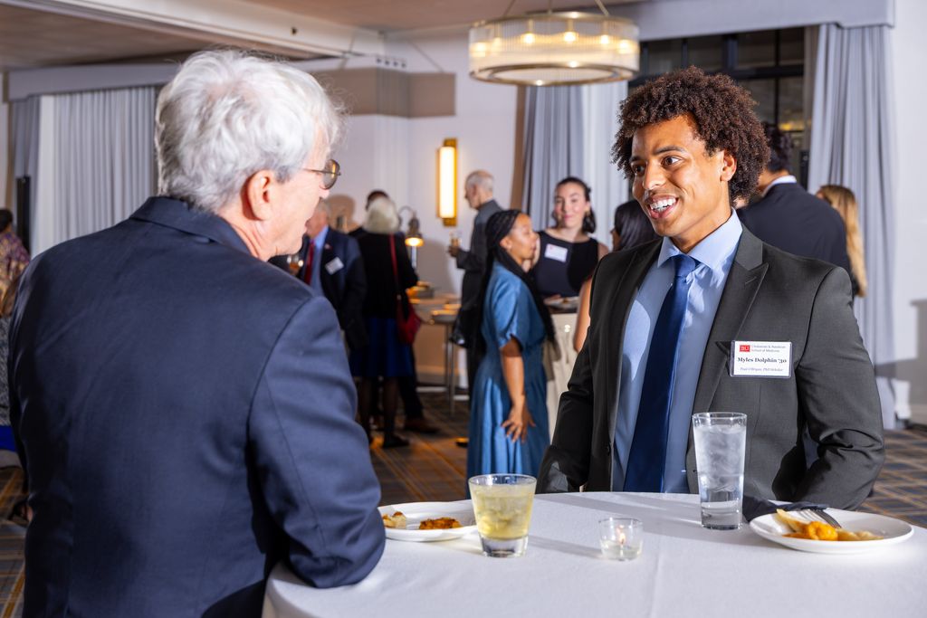 Two men stading at table talking and smiling