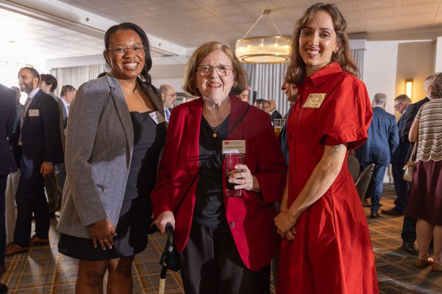 Three women stanging together at a party smiling