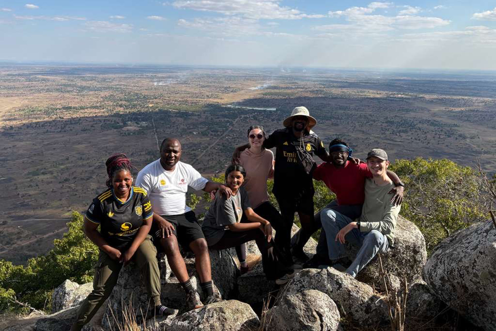 People sitting on rocks overlooking a valley, smiling
