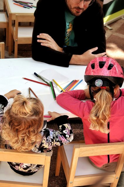 man with two children drawing at small table