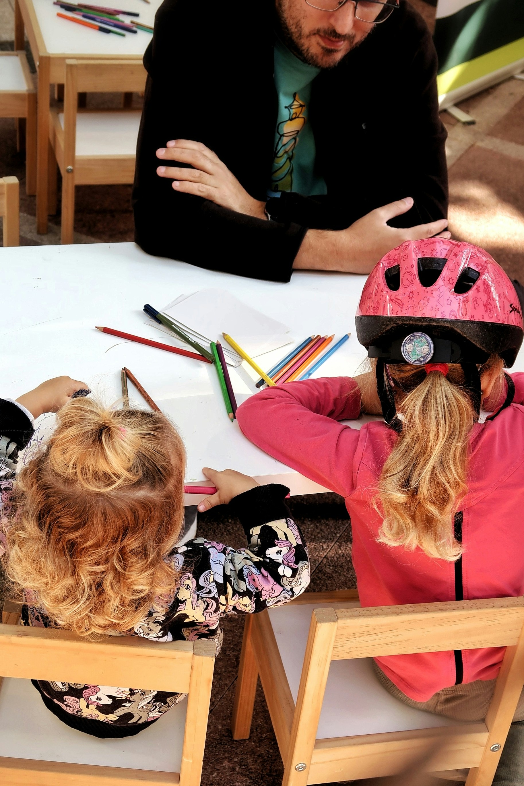 man with two children drawing at small table