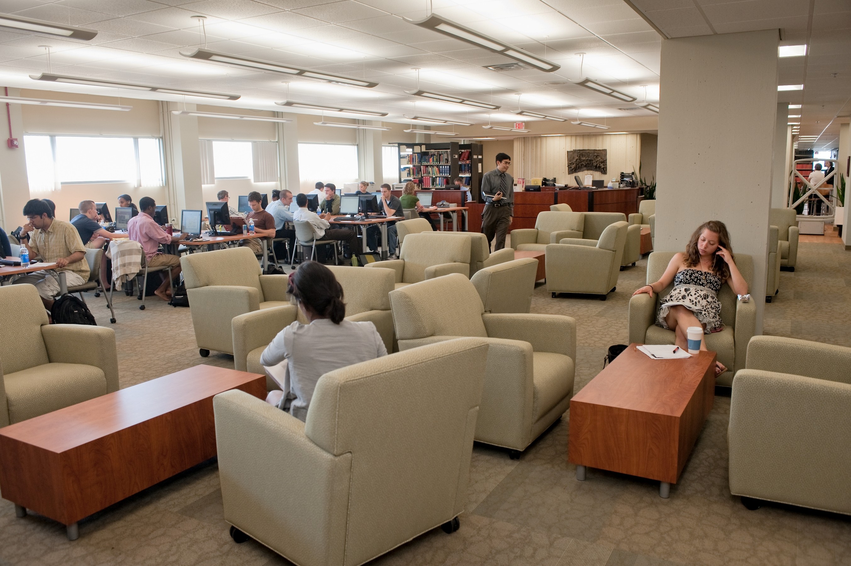 A large room with people sitting in comfy chairs and at tables.