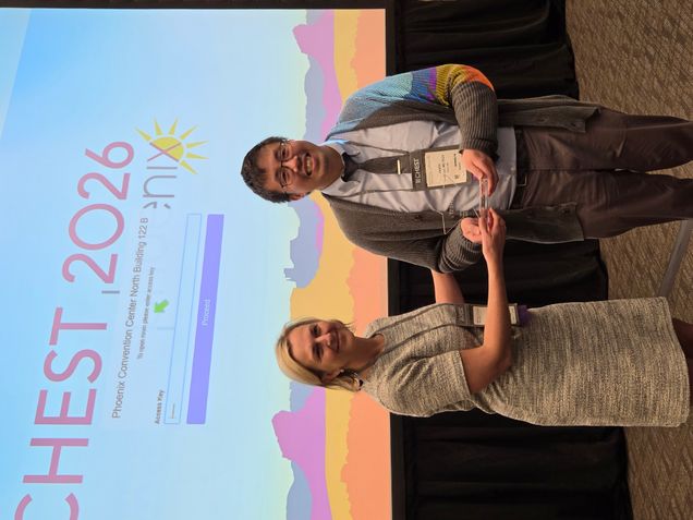 Man receiveing award from woman in front of backdrop that says CHEST 2026