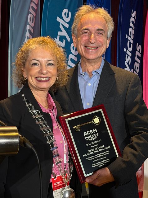Dr. Katz on right holding award standing next to woman