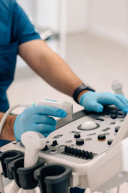 hands in blue gloves operating ultrasound machine