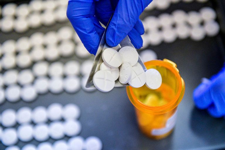 Methadone being scooped into a pill bottle.