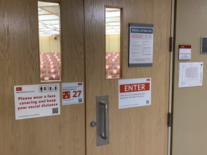 L 110 Door with maximum occupancy and masking requirements signage
