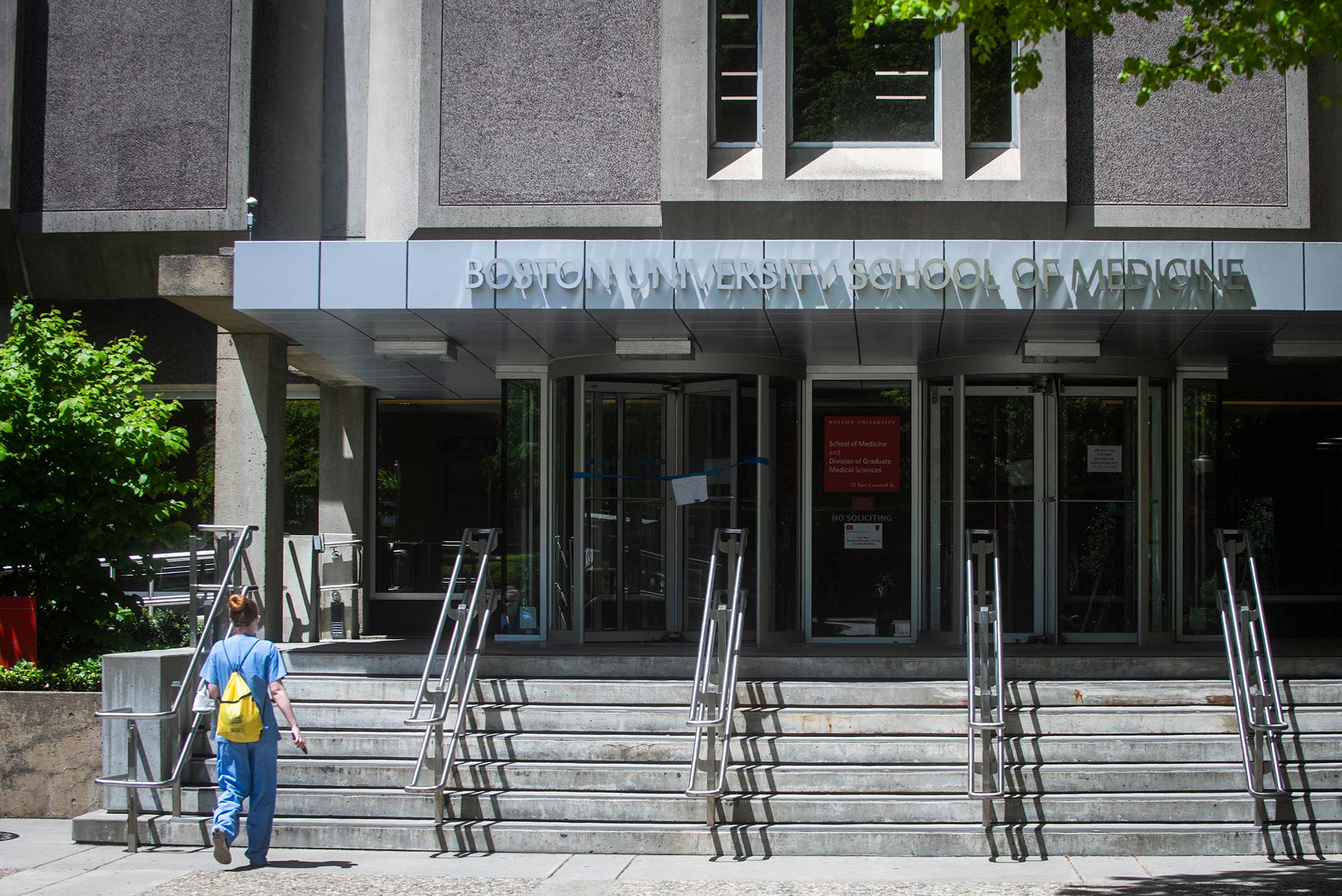 Image of BUSM Instructional Building entrance with female student walking upstairs toward entrance doors