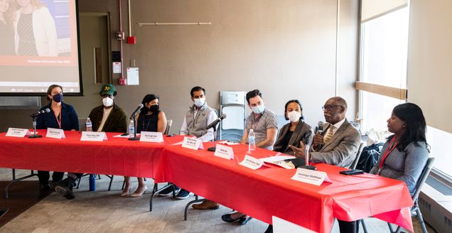 Eight people on one side of a table having a discussion