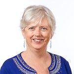 Woman with blond/sliver hair wearing blue top smiling broadly