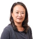 Head and shoulders of Catharine Wang wearing gray top, straight brown hair below shoulders, smiling gently