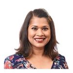 Head and shoulders shot of Nafisa Halim shoulder length brown hair, side parted broad smile, printed multicolored top