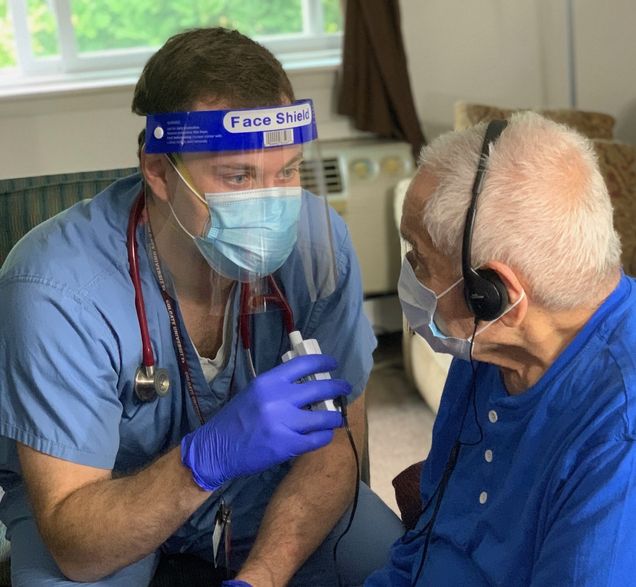 Fourth year medical student, Griffin speaking through a pocket talker with one of our patients.