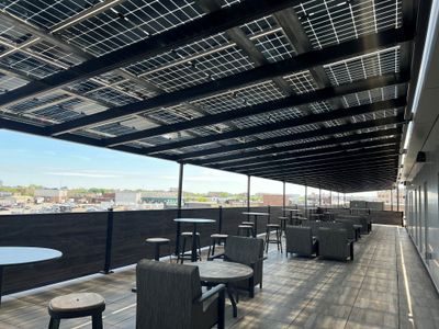 Newly renovated roof deck with grey furniture and an overhanging roof covered by solar panels