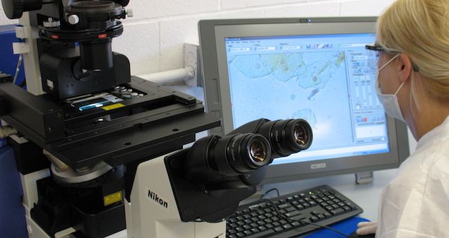 Student working on laser microscope in lab