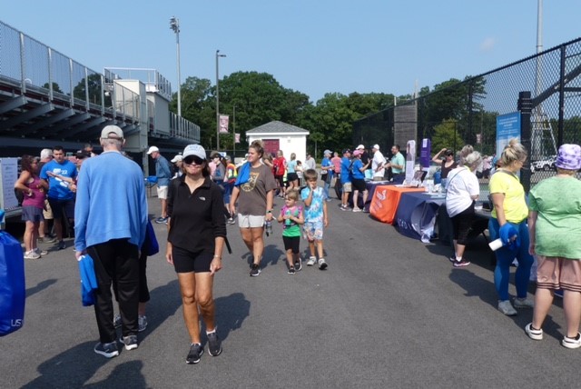 Participants walk around the venue to talk to other community members and get information at vendor tables on a sunny day.