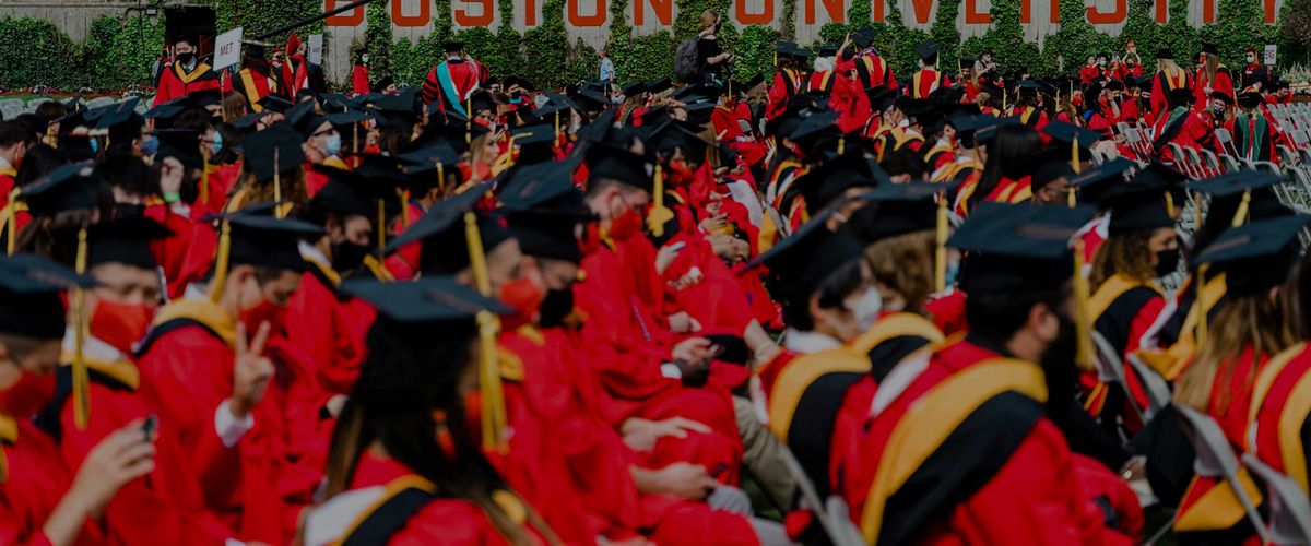 Boston University students sitting on Nickerson Field at graduation